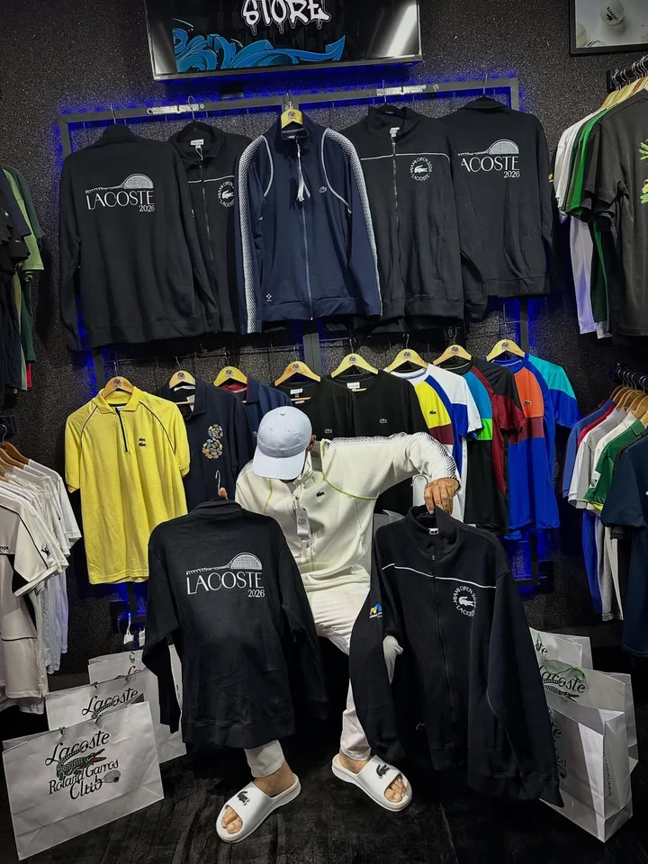 Interior da loja Mr.stor com araras de roupas de grife e iluminação neon